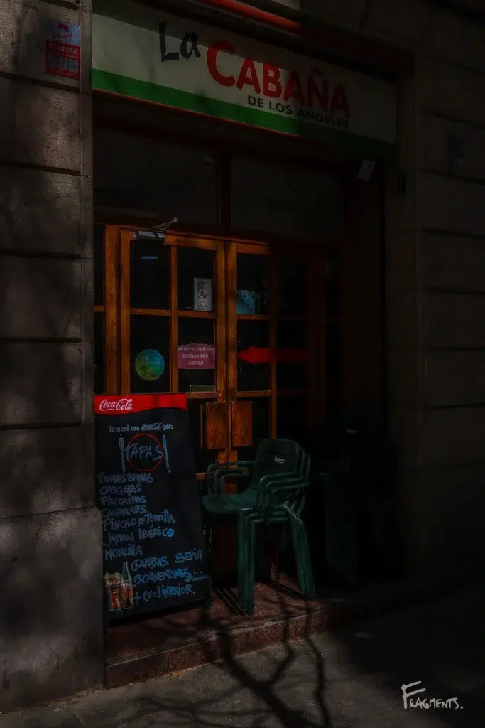 Voyage poétique et photographique à travers Barcelone : Chaises empilées devant un bar avec ombre de lumière