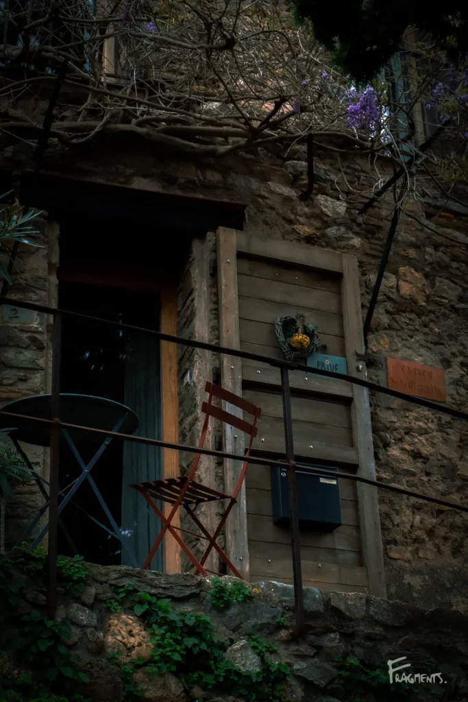 Voyage poétique et photographique à travers Castelnou : Chaise rouge et petite table juchées sur un balcon