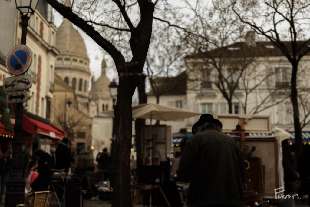 Voyage poétique et photographique à travers Paris : Peintre devant ses toiles sur la Place du Tertre à Paris, avec la basilique en arrière plan