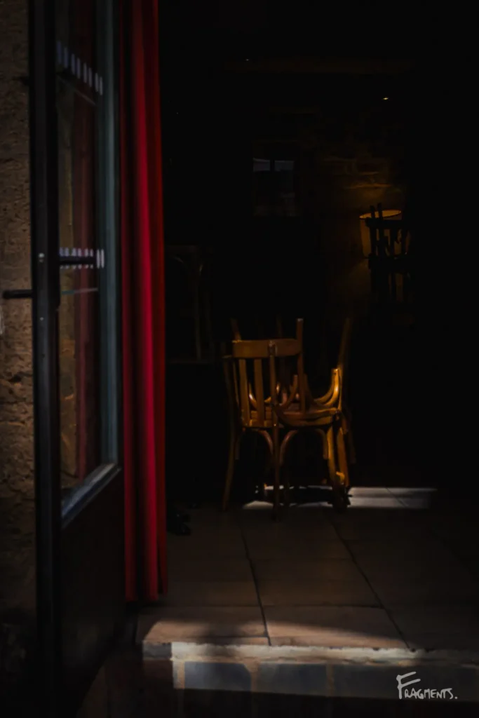 Chaises bar empilées dans l'entrebâillement d'une porte en clair obscur