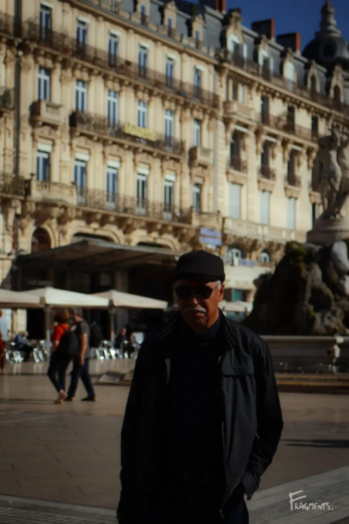 Homme habillé en noir au premier plan, sur la place de la Comédie à Montpellier
